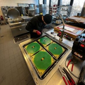 Reparatur durch Servicetechniker in der Gastroküche an einem Gastroherd...