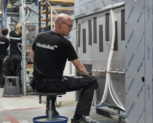 Im Bild sieht man Einblicke in die Fabrik Wexiödisk aus Schweden. Hier im Vordergrund sieht man einen Produktionsmitarbeiter bei der Fertigung einer Korbtransportmaschine. Wexiödisk ist ein Tochterunternehmen der Ali Group.